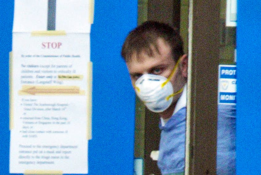 A staff member at York Central hospital in Richmond Hill, Ont., glances out the doors of the closed facility after fears the 2003 SARS outbreak was spreading further. At its peak, the outbreak caused people to avoid human contact, one epidemiology professor says.