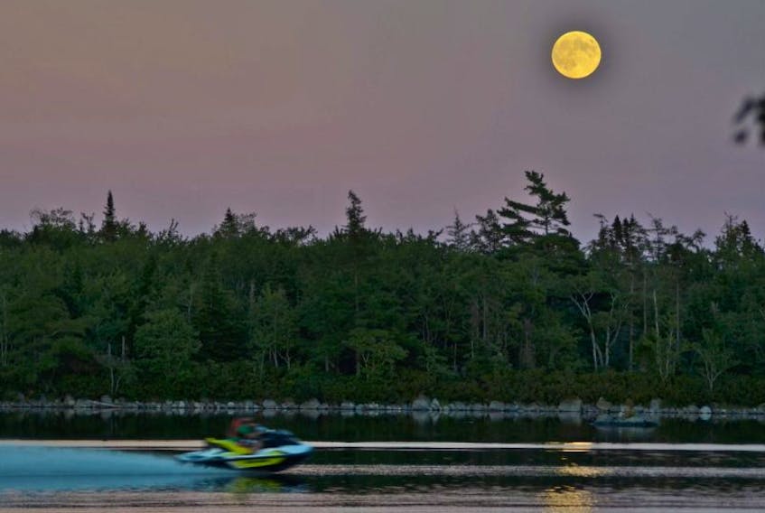 A boat whizzes by on Beaverdam Lake, Shelburne County as the supermoon rises.