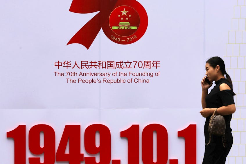 A woman walks past a billboard in Weifang with the founding date of People's Republic of China, ahead of the country's 70th anniversary.