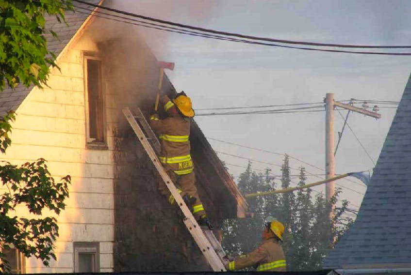 Sydney firefighters attack a fire on the exterior of a story and a half dwelling at 1191 George St., Sydney, which broke out at about 5:20 a.m. Tuesday. Gilbert MacIntyre, deputy chief of the Cape Breton Regional Fire Service, said someone called 911 after noticing black smoke in the area and while firefighters were responding an update came in of a vehicle on fire on George Street, close to a house. By the time firefighters arrived on the scene, the fire had extended up an exterior wall of the house to a bedroom on the upper level and to the soffits. It’s not known if anyone was inside at the time of the fire, but the occupants were outside when the firefighters arrived. PHOTO CONTRIBUTED/Ron Williams