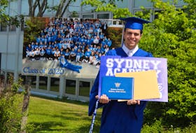 Stephen Hines, 18, holds his diploma and graduation lawn sign in front of a photo taken of the Sydney Academy Class of 2020, which was taken before schools were closed due in March due to COVID-19. This was set up outside the high school as another place for families to take photos of their grads after their private diploma ceremony. NICOLE SULLIVAN/CAPE BRETON POST