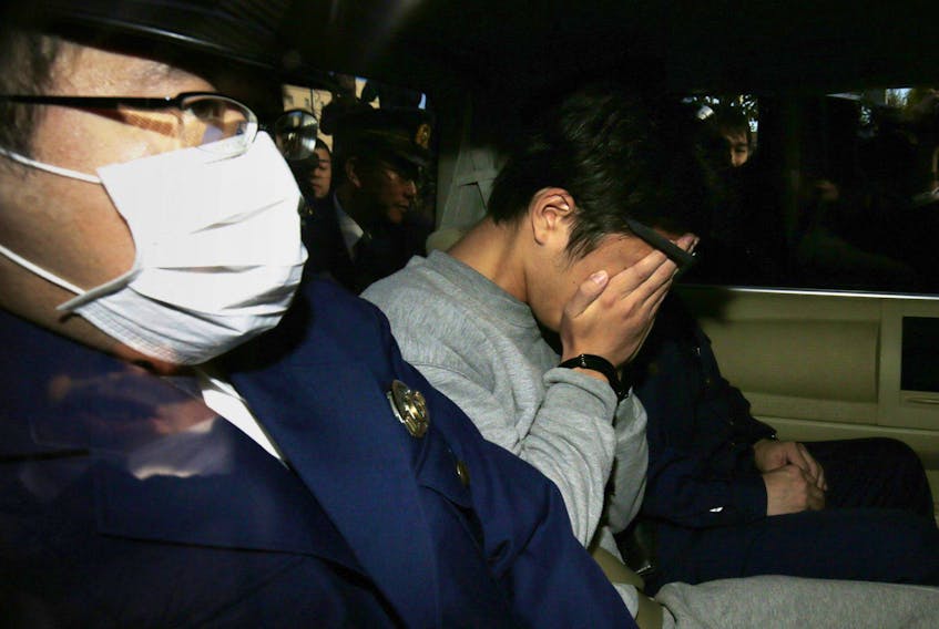 Suspect Takahiro Shiraishi (C) covers his face with his hands as he is transported to the prosecutor's office from a police station in Tokyo on November 1, 2017.