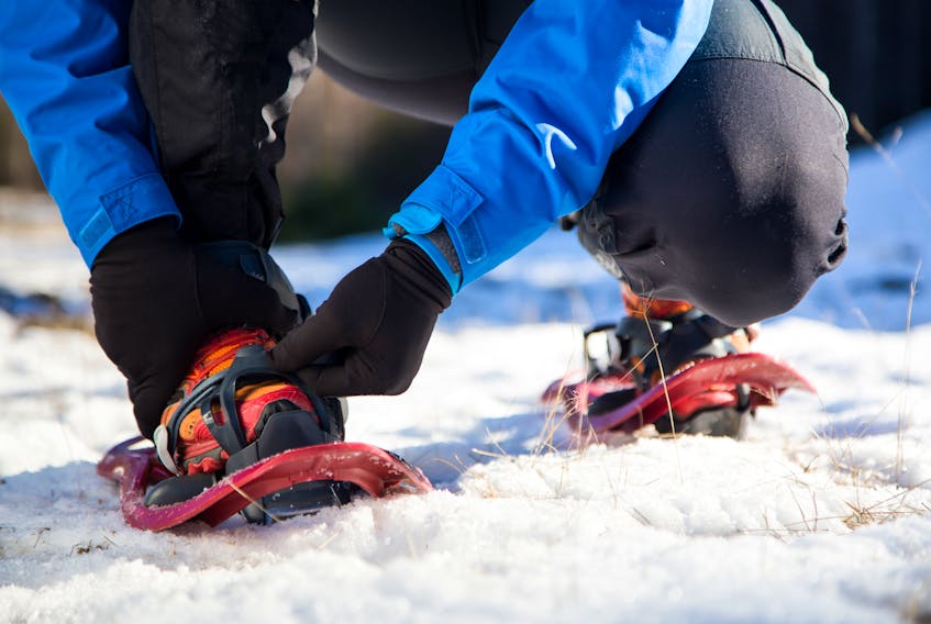 A person puts on snowshoes. Hike Nova Scotia is hosting free trail tours in Cape Breton as part of its annual Winter Guided Hike Series. Contributed