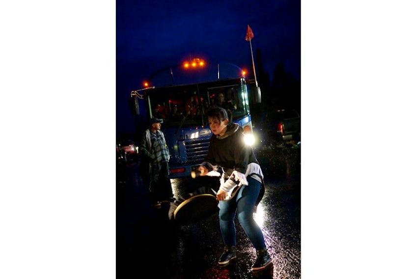 Drum dancer, Allyson Gear, stops a bus load of construction workers heading to the Muskrat Falls Dam construction site on Oct. 19.