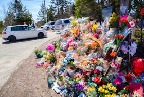 RCMP officers speak with a visitor near the large memorial in memory of the victims from the mass shooting seen at Portapique Beach Road in Portapique, N.S., on Thursday, April 30, 2020.