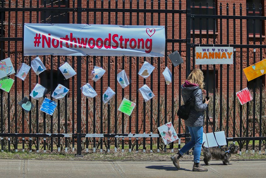 A woman walks past messages of support for residents and staff at Northwood placed across the street of the retirement and care facility in Halifax Wednesday May 6, 2020.