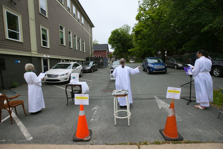 The clergy lead a prayer during a drive-in Sunday service for St. Mark's Anglican Church in a Macara Street parking lot on Sunday. - Tim Krochak