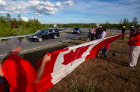 The Canadian flag is draped out as the hearse containing the late Sub-Lt. Matthew Pyke, who was taken to a Truro funeral home, passes by near the on-ramp to Highway 102 near Aerotech Park on Thursday evening.
