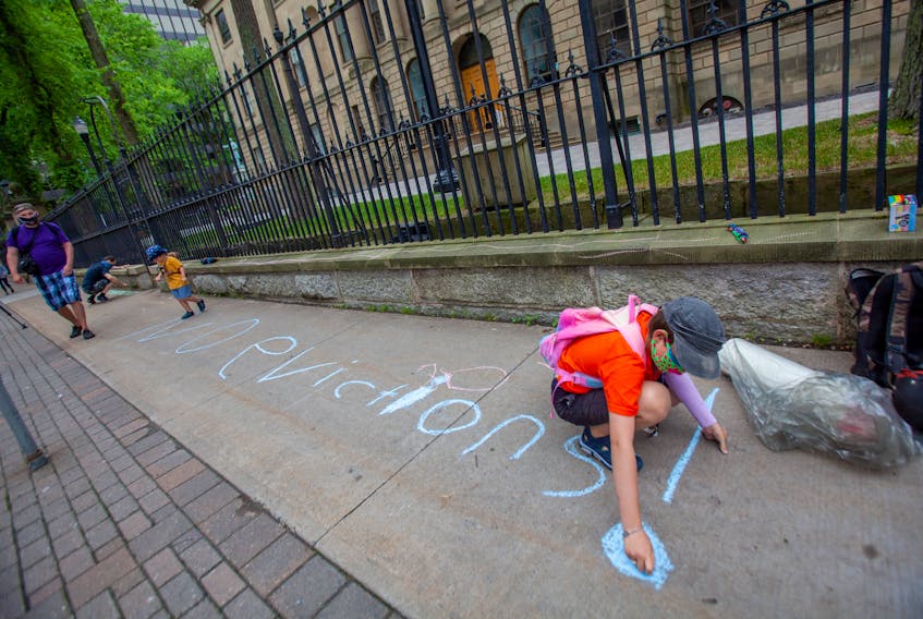 Xan Clark, 11, puts his message to the provincial government on the sidewalk in front of Province House Tuesday. Demonstrators were expressing the need to extend the ban on residential evictions that was put in place following the COVID-19 lockdown.