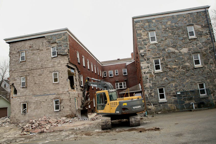 An excavator tears away at Ardmore Hall apartment building Friday despite a resident still living on the premises on Oxford and North Streets in Halifax.