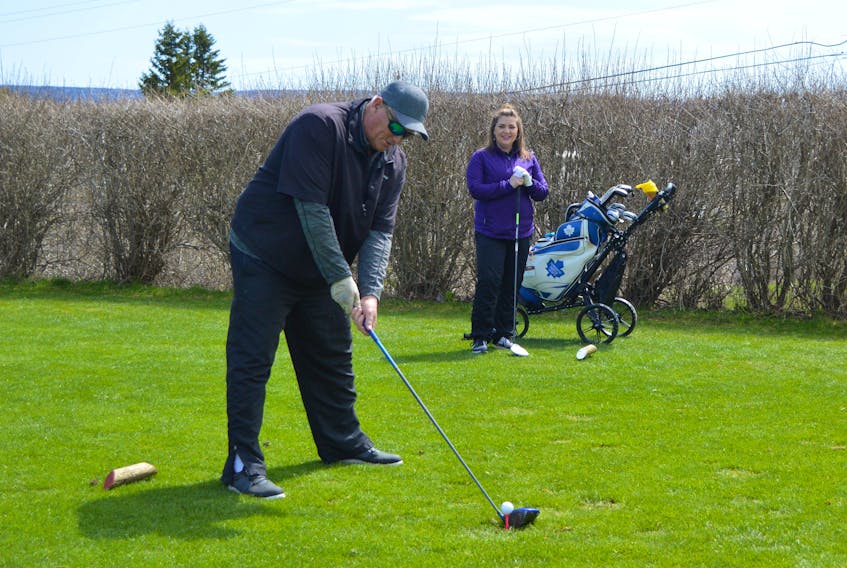 Danny Hamilton prepares to launch a drive from the first hole tee box at the Seaview Golf and Country Club on Sunday as Kendra Mullins-MacMillan looks on during opening day play at the North Sydney course. Like all golf courses in Nova Scotia, which were permitted to open over the Victoria Day long weekend, social distancing measures are in effect until the province dictates otherwise. The temporary conditions stipulate that only one person, family members excepted, can ride per cart and that golfers are to respect six-foot distancing. The club added a little more time between groups and put a shallow "saucer" in the cup on each hole so that golfers can easily retrieve their balls once holed. And, Seaview staff have new duties this season as they wipe down each and every cart after they come in from a round. The golfers who were out on opening day all seemed to be enjoying being back on the links. There was even a hole-in-one as Corey Musgrave recorded an ace on the par-3, 14th hole with a pitching a wedge. DAVID JALA/CAPE BRETON POST