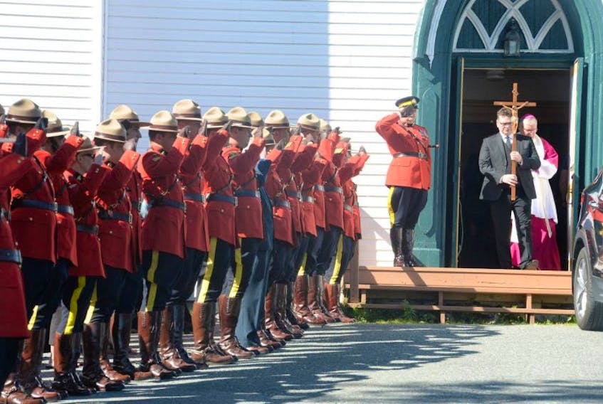 RCMP Regimental Sgt. Major Doug Pack (on steps) salutes as cross bearer Craig Follett leaves Sts. Peter & Paul Church in Bay Bulls on Friday following the funeral service of RCMP Cpl. Trevor O’Keefe, who died Monday. RCMP officers salute as O’Keefe’s remains are carried out of the church behind Follett, O’Keefe’s brother-in-law. 