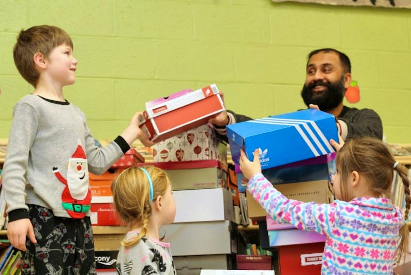 Holy Trinity Elementary School students Isaac Decker, Lily Konechny and Katie Goodyear help Project Kindness NL founder Hasan Hai organize shoeboxes of Christmas gifts for local children in need Friday morning. The Grade 1 students at Holy Trinity filled a total of 70 shoeboxes with toys, treats and other items. Project Kindness will pass the boxes on to the Single Parents Association of Newfoundland and Labrador, which will distribute them to families in time for Christmas. 