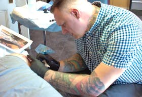 Tattoo artist Dave Munro works on client Craig Rogers at his Trouble Bound Studio on Water Street in St. John’s. Munro has a two-year waiting list for clients.