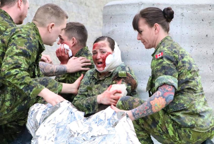 Pte. Sarah Kearley cries as if in pain as she is attended to by members of the CFS St. John’s Defence Force. In the background, Pte. Matt Mackenzie holds a bandage to his face.