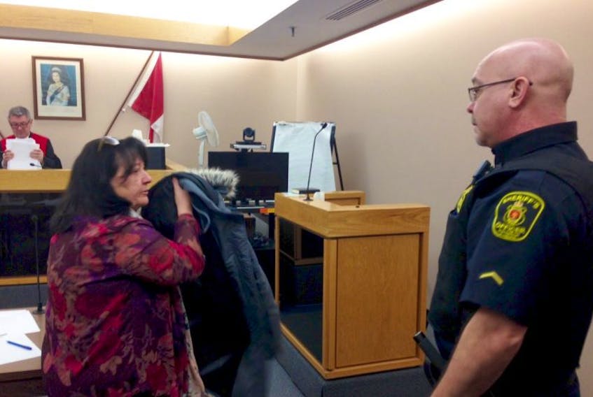 Julia Gosse turns to leave the courtroom with a sheriff’s officer at provincial court in St. John’s Friday after she was sentenced to 3 1/2 years in prison for defrauding and stealing from two local companies.