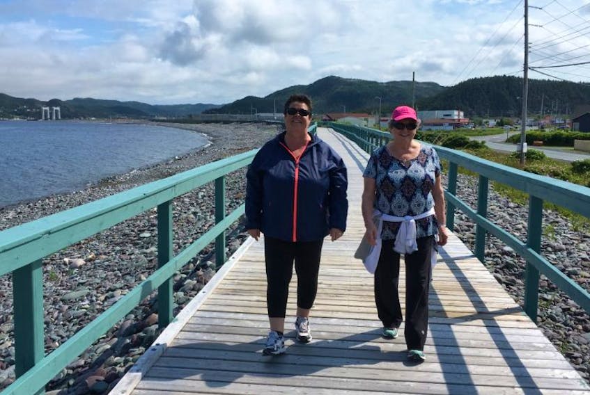 Donna Lambe (left) and Gail Ryan like to walk the boardwalk on the Placentia waterfront on a fine day. Both women recall past flooding in the community before protections such as the boardwalk and breakwater, and say sea level rise is not currently much of a concern.