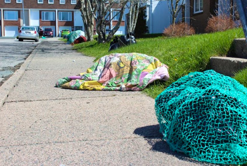 Household garbage awaits pickup at the curb on Cumberland Crescent in St. John’s, covered by nets and blankets, or uncovered. Some of the covered garbage in the area was being picked at by crows, sticking their beaks under the coverings.