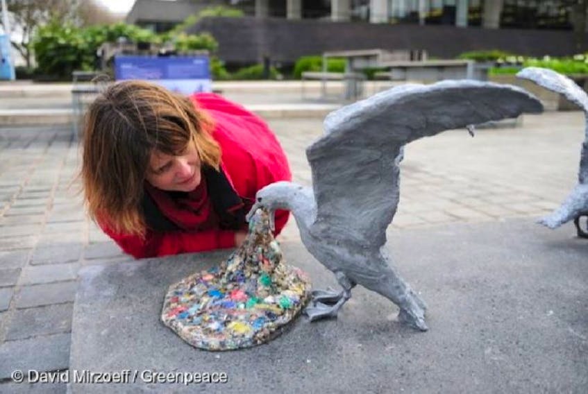 A woman takes a close look at “Plasticide,” a sculpture by Jason deCaires Taylor of a seagull vomiting plastic pieces.