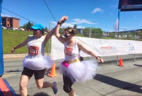 Susan Locke,left, joins hands with Andrea O'Neill as they complete the 10-K Run for Women, finishing on The Boulevard by Quidi Vidi Lake  just after 10:30 Sunday morning. The two said they ran with a group of about 100 women who all wore tutus and Princess Leia hair buns.