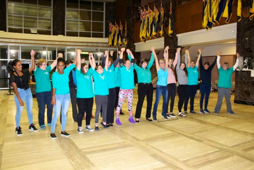 Ovarian cancer survivors, patients and supporters join in a dance after they lit the Confederation Building teal on Monday to recognize Ovarian Cancer Awareness Month. 