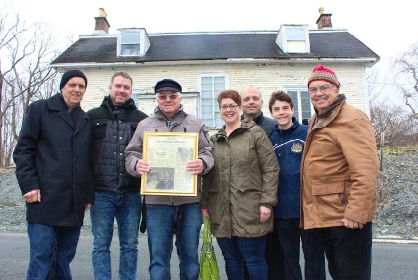 Some of the descendants of gardener John White — from left, Paul Manning, Bryan K. Manning, Bryan F. Manning, Tammy Bishop, Stan Cook Jr., Sebastian Cook and Stan Cook Sr. — gathered beside Richmond Hill Cottage in St. John’s on Monday. The senior Manning is holding a copy of a 1999 story from The Telegram called “Life with the Lindberghs,” chronicling a family tie to the old estate.