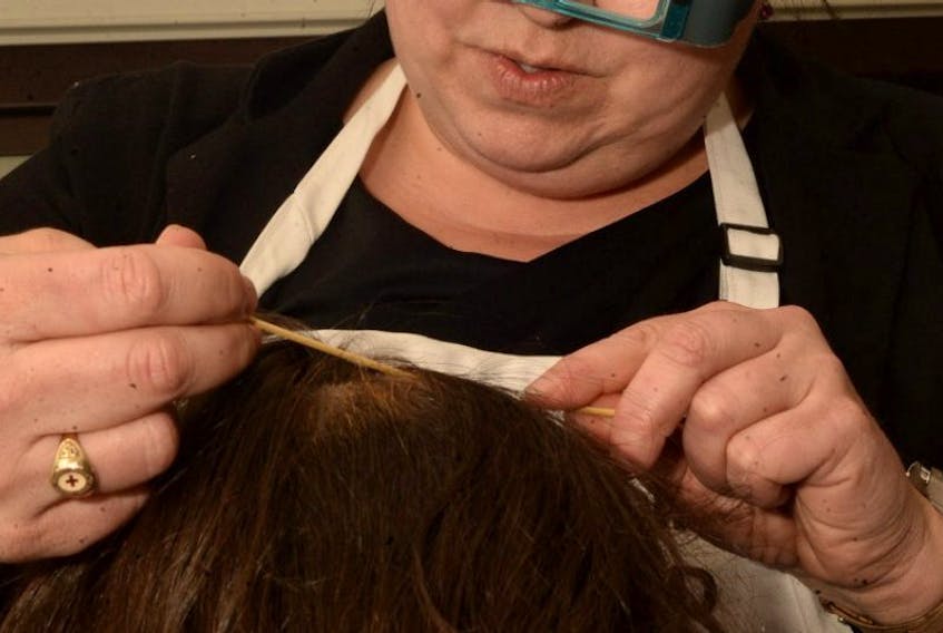 Tammy-Lee Joyce demonstrates how she uses sticks to search through hair for traces of head lice at her St. John’s home on Monday night. Joyce is in the business of getting rid of head lice. As owner of the franchise Lice Squad NL, she visits families’ homes to use non-toxic products to treat head lice.