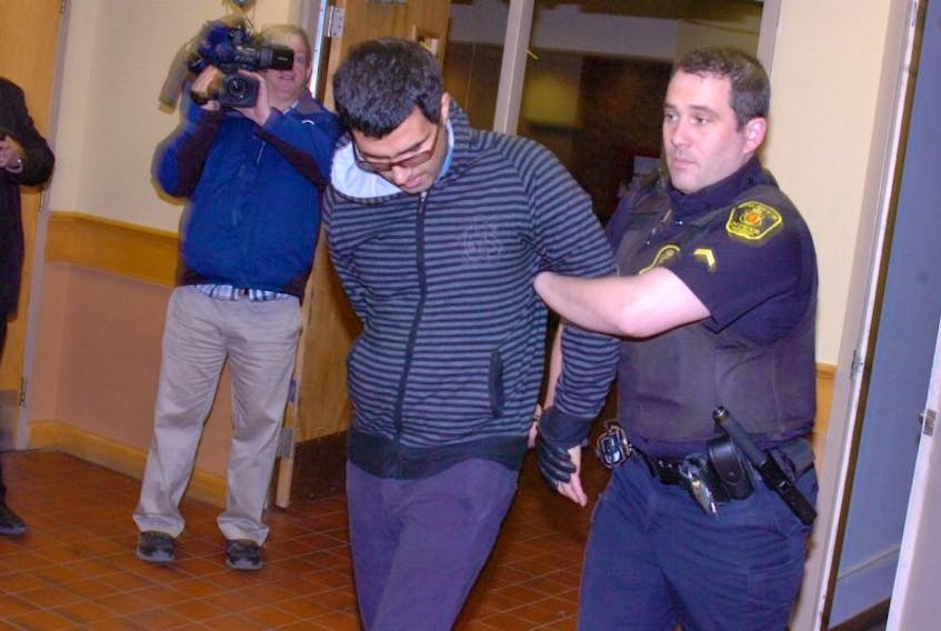 Masih Allahbakshi tries to hide his face from reporters Tuesday at provincial court in St. John’s.