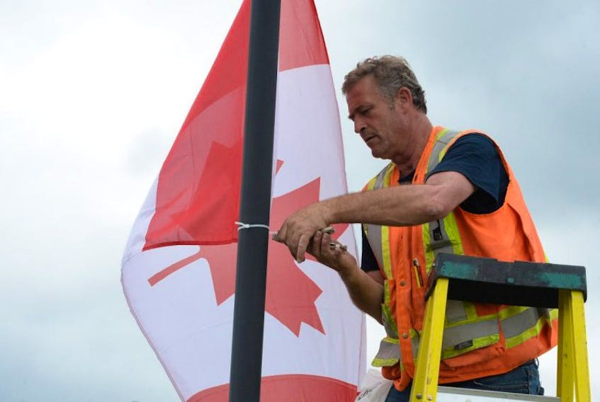 Mike Donovan installs Canadian flags on Thursday in preparation for Canada Day.
