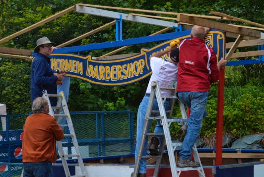 Members of Anchormen Barbershop Chorus hang the sign above their booth Tuesday afternoon.