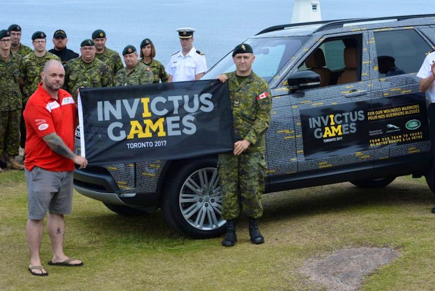 Veteran and Invictus Games athlete Tyson Tulk (left) and Cpl. Josh Cooper of CFS St. John’s hold the official flag for the 2017 Invictus Games at Cape Spear Wednesday as other members of the military — active and retired — look on. The flag, and the vehicle shown at right, will travel the country spreading awareness about the games and its spirit before heading to the opening ceremonies in Toronto in late September.