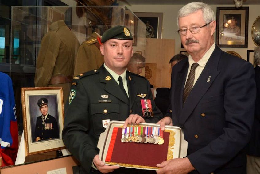 Maj. Kyle Strong (left), deputy commanding officer of the Royal Newfoundland Regiment, First Battalion, accepts the service medals from Fraser Eaton, son of Lt.-Col. Cam Eaton (who is pictured in framed photograph).