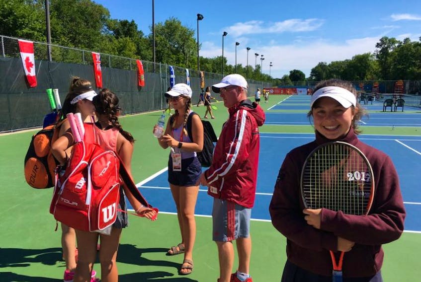 Newfoundland and Labrador tennis player Ashley Stringer poses for a photo at the Winnipeg Lawn Tennis Club, while her Canada Games teammates, Emma Murray, Olivia Casey and Jasmine Rahman, talk with coach Mike Meaney prior a Sunday practice session. Tennis competition at the Games begins today.