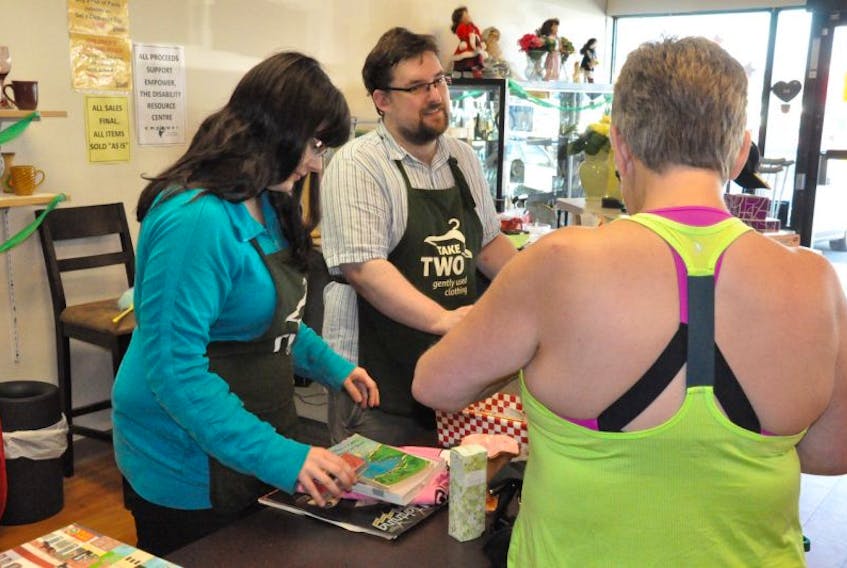 Michelle McDonald (left) and Mark O’Shea ring in a customer’s purchase at Take Two Gently Used Clothing and More, a second-hand clothing store started by Empower, the Disability Resource Centre.