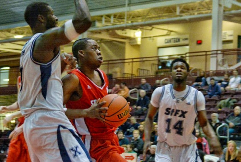 The Memorial Sea-Hawks’ Daniel Gordon looks to move the ball past the defence of Kevin Bercy (7) of the St. Francis Xavier X-Men during weekend AUS men’s basketball action at the Memorial Field House. Akil Charles (14) of the X-Men looks on. Gordon scored 27 points off the bench as Memorial downed St. FX  98-91 Sunday for a sweep of their two-game weekend series.
