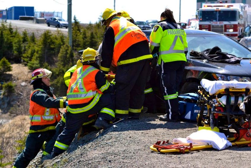 Firefighters balance on an embankment as they extricate the victim of a head-on collision in Conception Bay South Saturday afternoon.
