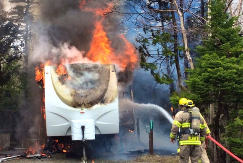 St. John's Regional Fire Department  firefighter Darryl Gillingham and firefighting student Morgan Janes attack an RV fire at Pippy Park in St. John's Wednesday.