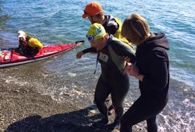 Kim Davis is helped out of the water at Bell Island after swimming the Tickle Sunday morning.