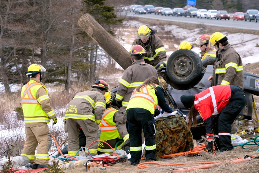 Emergency officials work at the scene of a car crash on Pitts Memorial Drive Thursday.