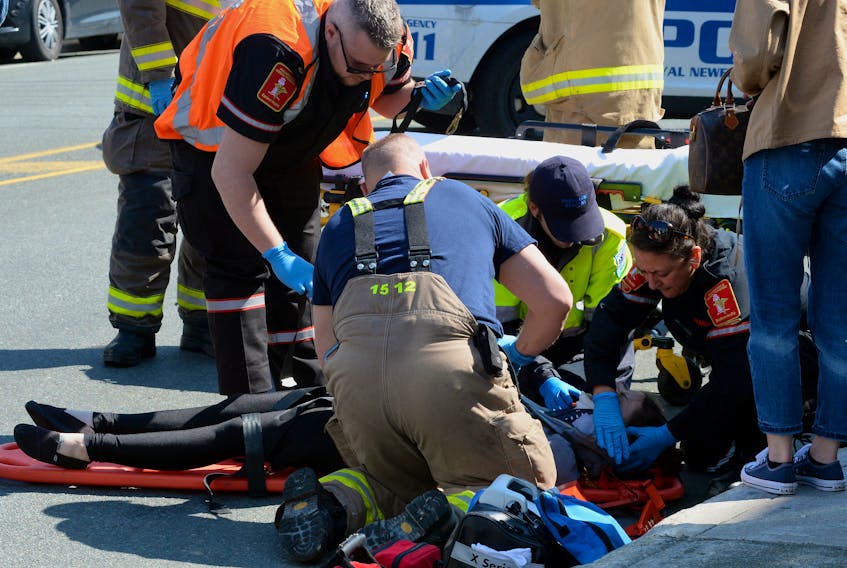 A female pedestrian is given medical attention after she was struck by an SUV on Queens Road Sunday. Keith Gosse/The Telegram
