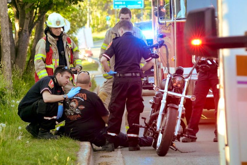 An injured motorcyclist who was rear-ended by a pickup truck driver in downtown St. John’s is checked by a paramedic following the incident.