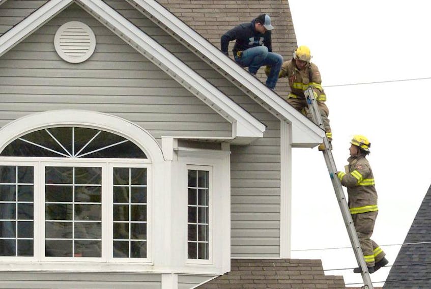 Firefighters help a man from a roof in Mount Pearl Saturday afternoon after his co-worker fell two storeys.