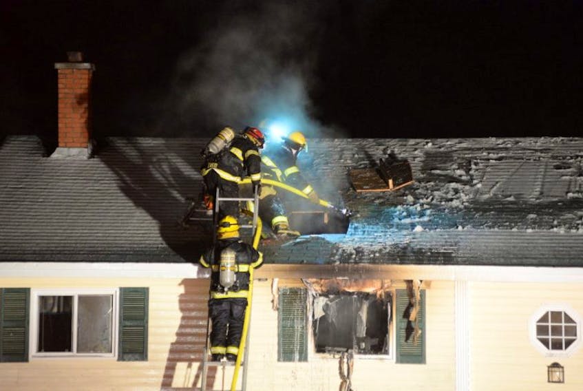 Torbay volunteer fire department firefighters spray water in through a roof after a New Year's Eve house fire caused extensive damage to a home in Torbay Saturday night. 