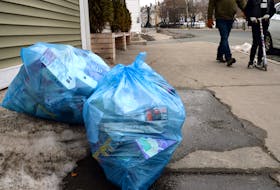 Two people make their way past uncollected recycling on Military Road Monday afternoon.  Keith Gosse/The Telegram
