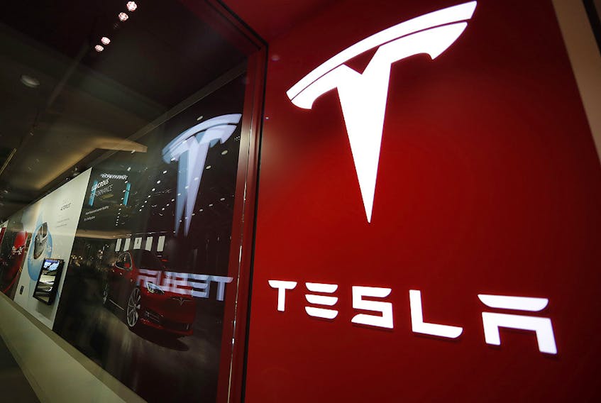 In this Feb. 9, 2019, file photo, a sign bearing the company logo is displayed outside a Tesla store in Cherry Creek Mall in Denver. 