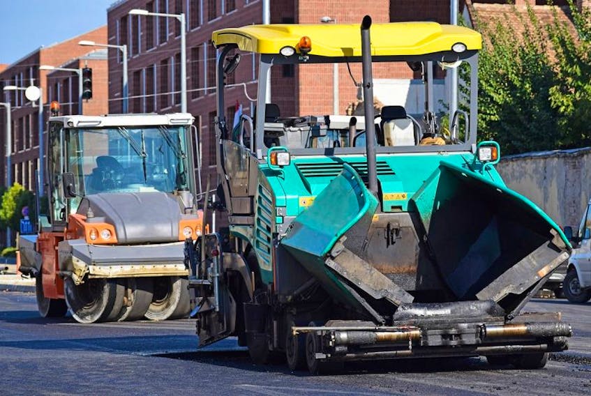 FILE PHOTO: Asphalt paving vehicle and road roller at a road construction.