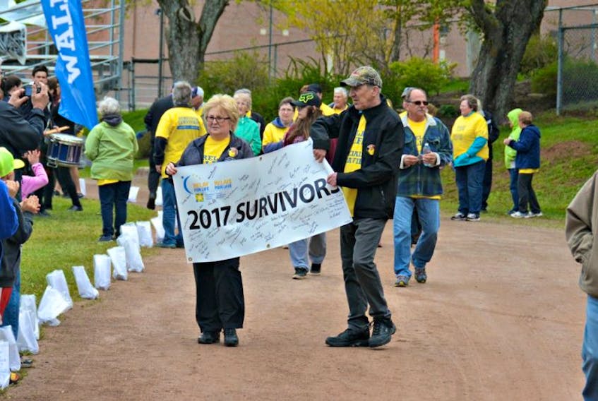 Eileen Sears (left) and her brother Nelson Blanchard hold the Relay for Life survivor banner in memory of their brother Wayne who passed away two months ago from a cancerous brain tumour.
