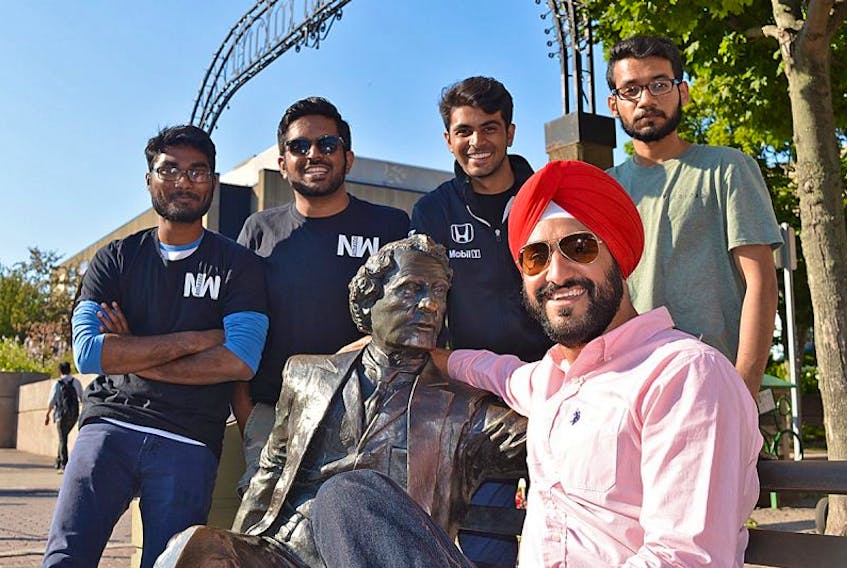 Gagandeep Sehgal, seated, and his team from Namaste World, from left, Prashanth Gunti, Vimal Ramaka, Alkarim Bhalesha and Adi Vella, ham it up with the statue of Sir John A. MacDonald in Charlottetown. Their new website profiles immigrant successes in Prince Edward Island.