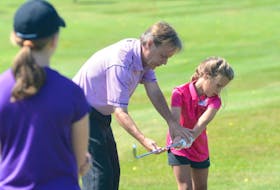 Belvedere head professional Marshall McMahon helps Reid Hart during a girls golf camp in August in Charlottetown.