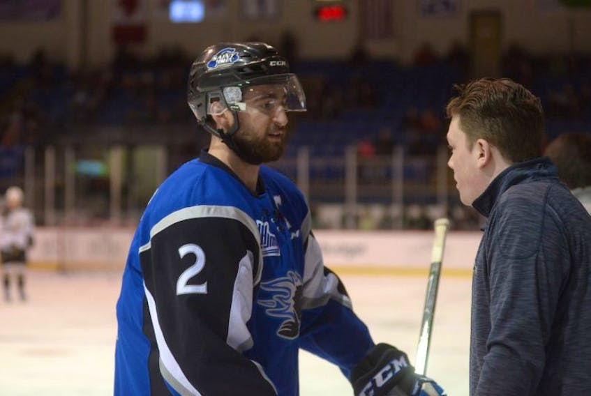 Saint John Sea Dogs equipment manager Tyler Jay, right, speaks to defenceman Bailey Webster, left, speaks with defenceman Bailey Webster before a game in Charlottetown on March 17. Webster wore the captain’s C for the contest.